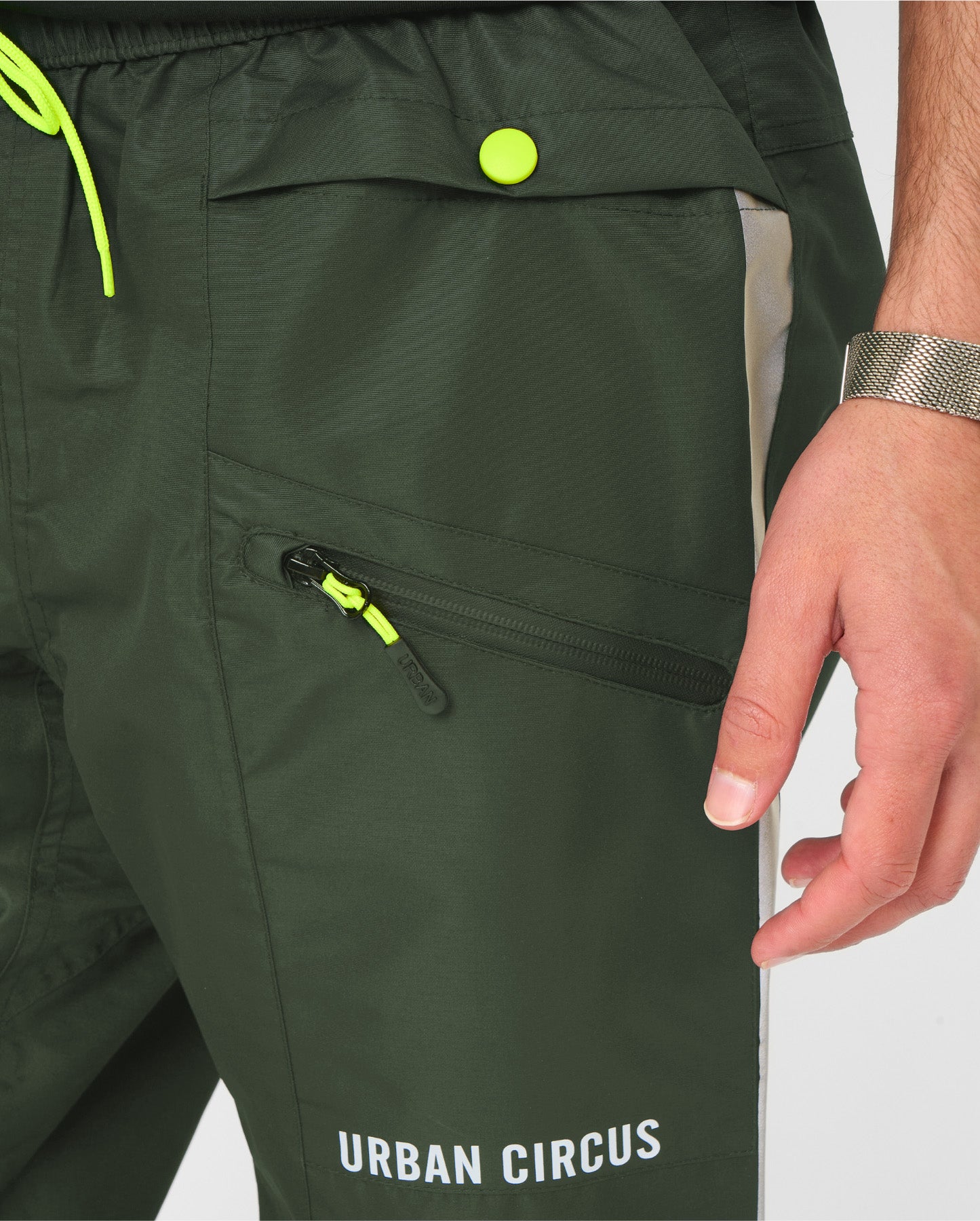 Zoom sur le tissu technique et les poches du pantalon de pluie kaki IYUC Urban Circus, matière imperméable et légère.