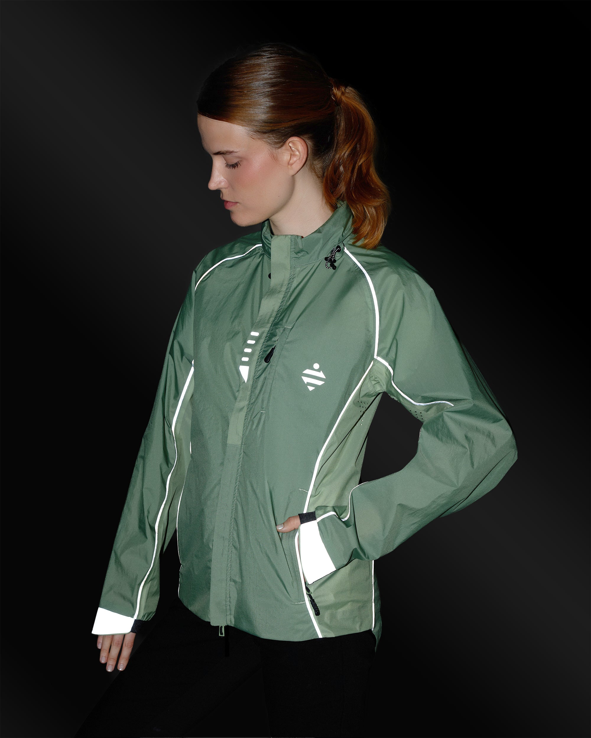 Ultraleichte, atmungsaktive Jacke in Salbeigrün mit reflektierenden Details an einer Frau bei Nacht